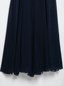 Detailed close-up of navy blue polka dot chiffon fabric with elegant vertical pleats