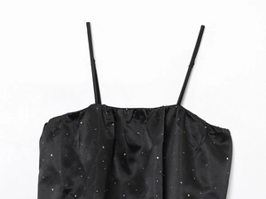 Détail du caraco en satin noir avec strass scintillants et encolure froncée élégante