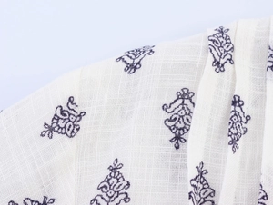 Macro shot of ivory linen fabric featuring ethnic floral patterns and woven texture