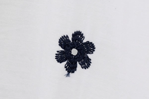 Detail of high-density navy blue floral embroidery on white cotton poplin fabric