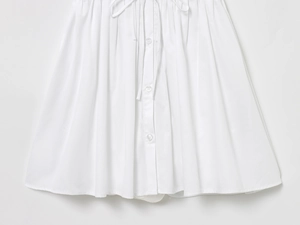 Detail of white cotton linen dress showing single-breasted buttons and drawstring waist