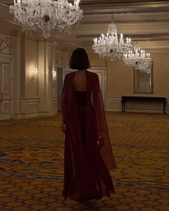 Elegant back view of burgundy evening gown with mesh cape in a luxury ballroom setting