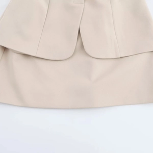 Close-up of beige woven dress fabric showing clean stitching and layered ruffle details