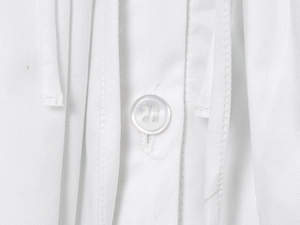 Detailed close-up of a white four-hole button and twill fabric texture on a summer dress
