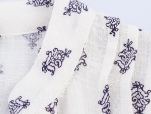 Detailed macro view of French floral pattern on white linen long sleeve shirt fabric