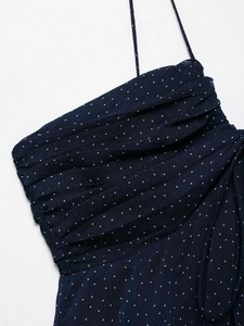 Detailed view of the navy blue dress with white polka dots and delicate pleated chest area