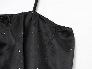 Détail du haut en satin noir avec strass argentés et fines bretelles de l'épaule