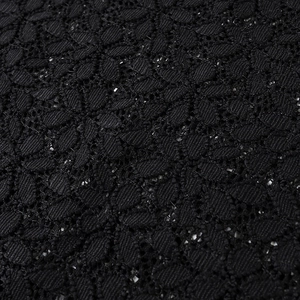 Macro view of black floral crochet lace fabric with intricate hollow-out texture