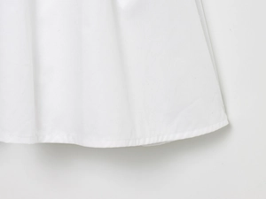 Detailed close-up of white dress hem showing high-quality twill fabric texture and clean seams