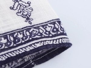 Close-up detail of ethnic floral print on white cotton-linen fabric with stitching