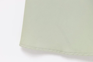Detailed view of the fine stitching and light green fabric texture on the dress hem