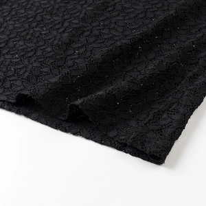Detailed close-up of intricate black lace fabric with floral patterns on the sleeve