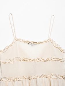 Détail de la bordure à volants et fines bretelles sur un haut camisole en maille beige