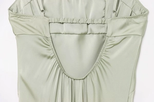 Detail of sage green satin dress featuring adjustable straps and gathered back design