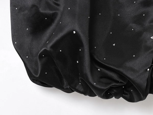 Macro de tissu satiné noir avec des strass étincelants et une texture de soie élégante