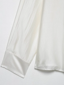 Detailed view of the wide cuffs and smooth stitching on a white satin long sleeve shirt