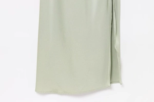 Detailed view of sage green satin dress hem featuring a side slit and fine stitching
