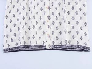 Detail of white cotton linen shirt showing blue ethnic prints and beige buttons