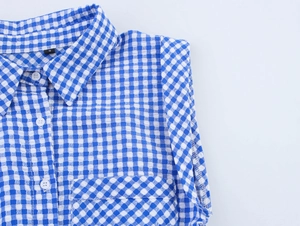 Close-up of blue plaid seersucker fabric texture with white resin buttons and collar