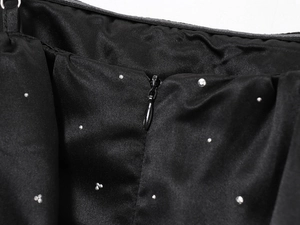 Détail du tissu en satin noir avec strass brillants et fermeture éclair invisible