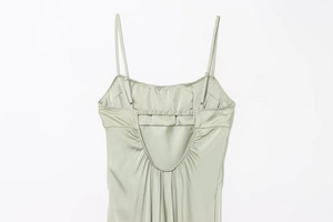 Detail of sage green satin dress featuring adjustable straps and back ruching detail
