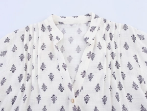 Detail of floral printed linen shirt showing V-neckline with pleated texture and button