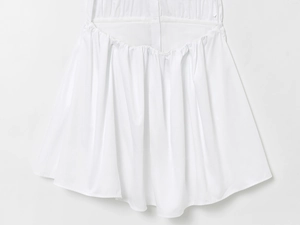 Close-up detail of white summer dress featuring elegant gathered waist and pleated texture