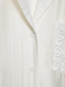 Detailed view of the lapel, white buttons, and geometric embroidery on the satin pocket