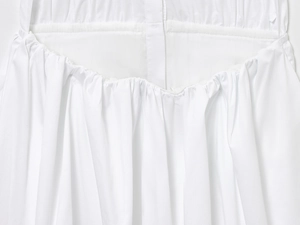 Detail view of white summer dress showing ruched fabric texture and button placket