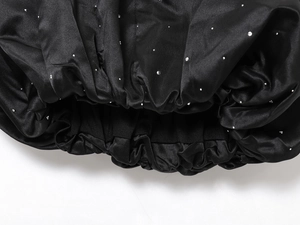 Détail du tissu en satin noir avec des strass et un design d'ourlet plissé élastique