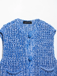 Close-up of blue chunky knit vest featuring large buttons and textured hollow stitch