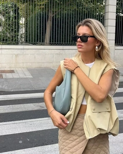 Detail of light beige oversized faux leather vest featuring utility pockets and front zipper