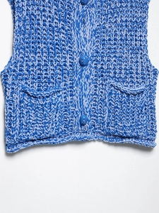 Detail of blue and white chunky knit vest with front buttons and two patch pockets