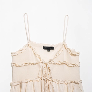 Haut caraco chic en maille beige avec volants, laçage frontal et détail col en V doux