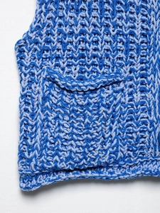 Detail of blue textured chunky knit vest featuring marled yarn and a functional patch pocket