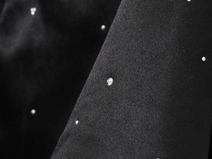 Détail macro du tissu satiné noir avec strass argentés brillants sur le haut bustier