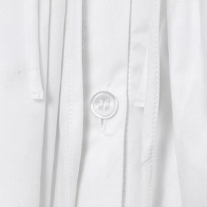 Close-up of a white backless dress with fine cotton texture and button detail