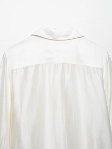 Detail view of smooth white satin shirt collar and back yoke with silky texture