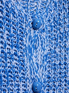 Macro shot of two-tone blue chunky knit vest texture with glossy resin buttons