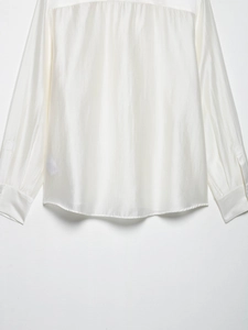 Close-up of pearl white satin long sleeve shirt showing premium glossy fabric and stitching