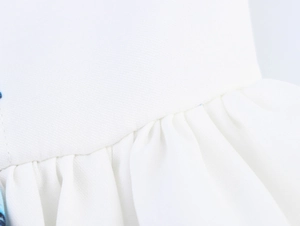 Detailed macro view of white fabric ruffles and blue floral print on dress hemline