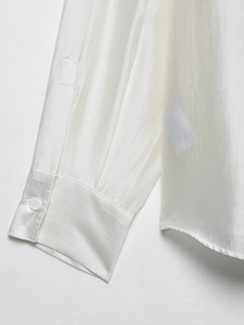 Macro shot of silk satin shirt cuff with pearl white button and fine stitching detail