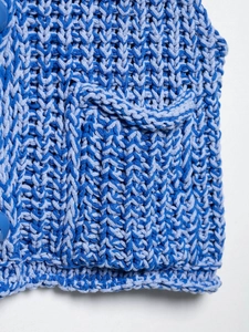 Close-up of blue chunky knit vest featuring textured yarn and side button detail