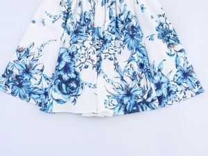 Detailed view of white skirt hem featuring elegant blue floral jacquard pattern print