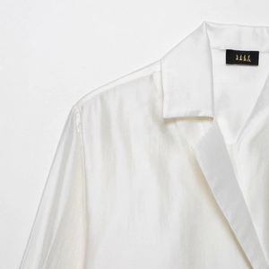 Elegant white satin long sleeve shirt featuring pocket embroidery and glossy fabric texture