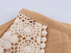Dettaglio del tessuto in lino beige con pizzo all'uncinetto bianco e finitura a pompon