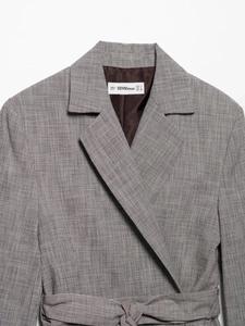 Detailed view of grey houndstooth blazer collar with fine fabric texture and inner lining