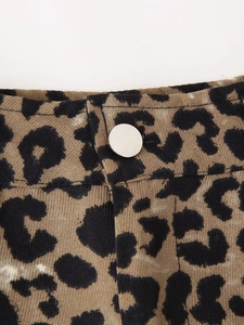Detail of leopard print fabric shorts with a polished silver button and twill texture