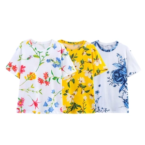 Detalle de tres camisetas veraniegas con estampado floral en blanco y amarillo suave