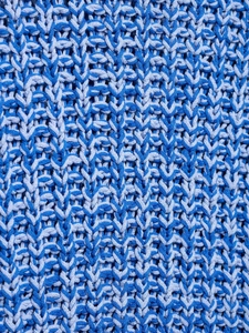 Close-up of blue chunky knit fabric showing detailed stitching and textured weave pattern